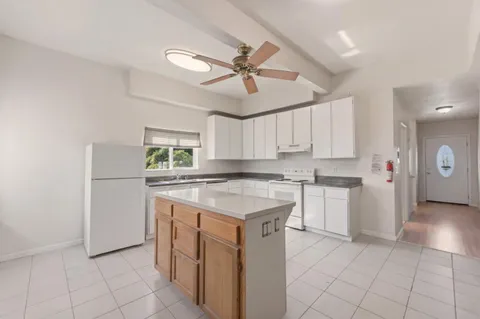 a kitchen with a stove a refrigerator and white cabinets
