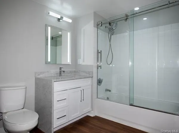 a bathroom with a granite countertop toilet a sink and shower
