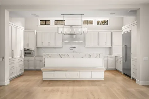 a spacious white kitchen with white cabinets and stainless steel appliances