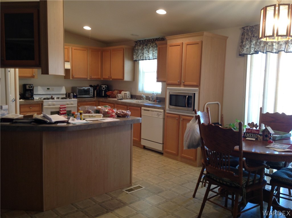 4214 Cordes Road Golden Valley, AZ 86413 - Photo 5 of 49 a kitchen with stainless steel appliances granite countertop a stove top oven a sink a dining table and chairs