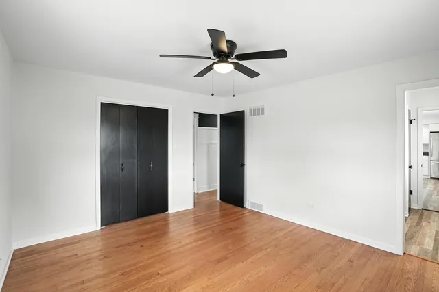 a view of empty room with wooden floor and ceiling fan