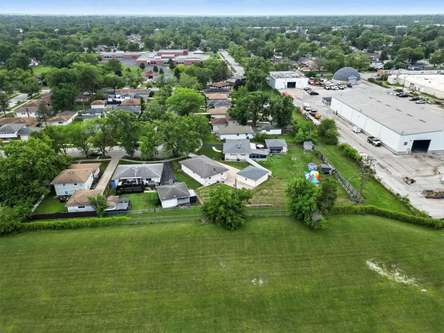 an aerial view of residential houses with outdoor space and trees