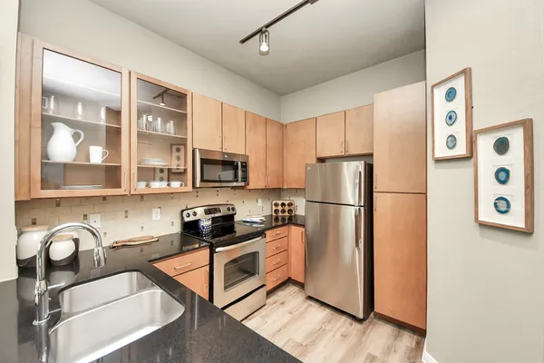 a kitchen with stainless steel appliances granite countertop a sink and a wooden cabinets