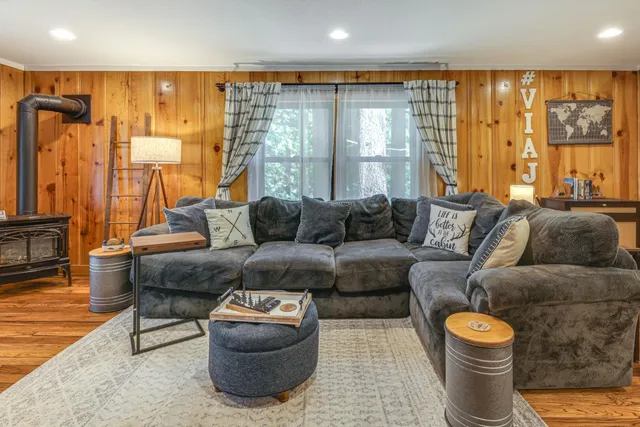 a spacious bedroom with a bed a mirror on dresser and a wooden floor