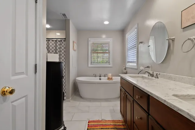 a bathroom with a sink double vanity granite tub shower and a mirror