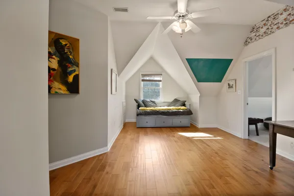 a view of a livingroom with wooden floor a ceiling fan and staircase