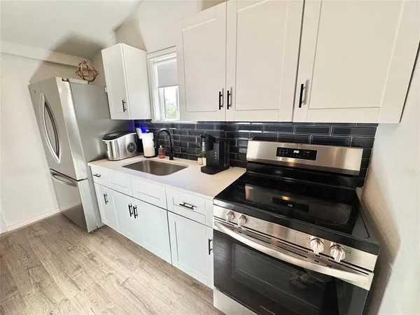 a kitchen with granite countertop a refrigerator stove and sink