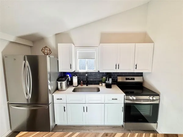 a kitchen with a sink a refrigerator and cabinets