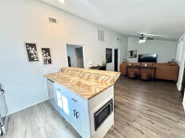 a living room with stainless steel appliances kitchen island hardwood floor and a sink