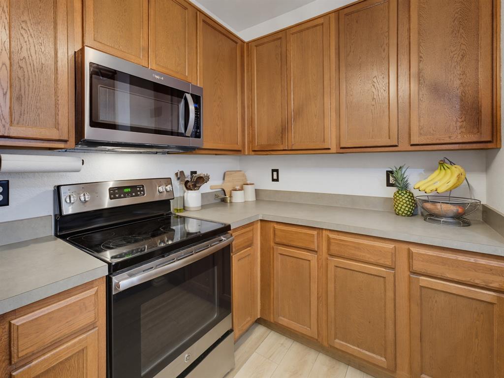 600 Stirling Road Rhome, TX 76078 - Photo 17 of 38 Kitchen featuring wood cabinetry, stainless steel range and microwave, light-toned countertops, and wood-finish flooring