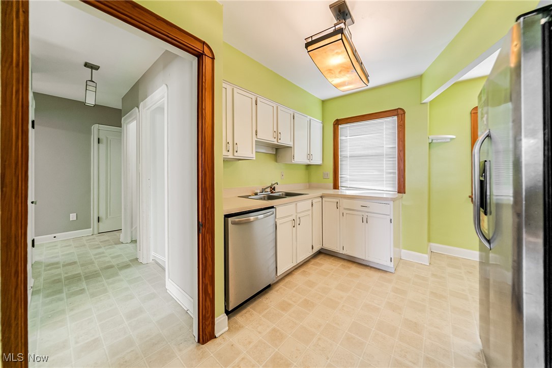 6711 Forest Avenue Parma, OH 44129 - Photo 11 of 33 Kitchen with stainless steel appliances, light countertops, white cabinets, light floors, and decorative light fixtures