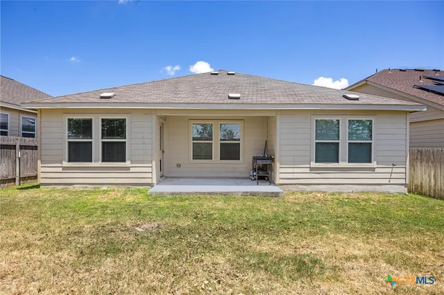 a view of a house with a yard and a large tree