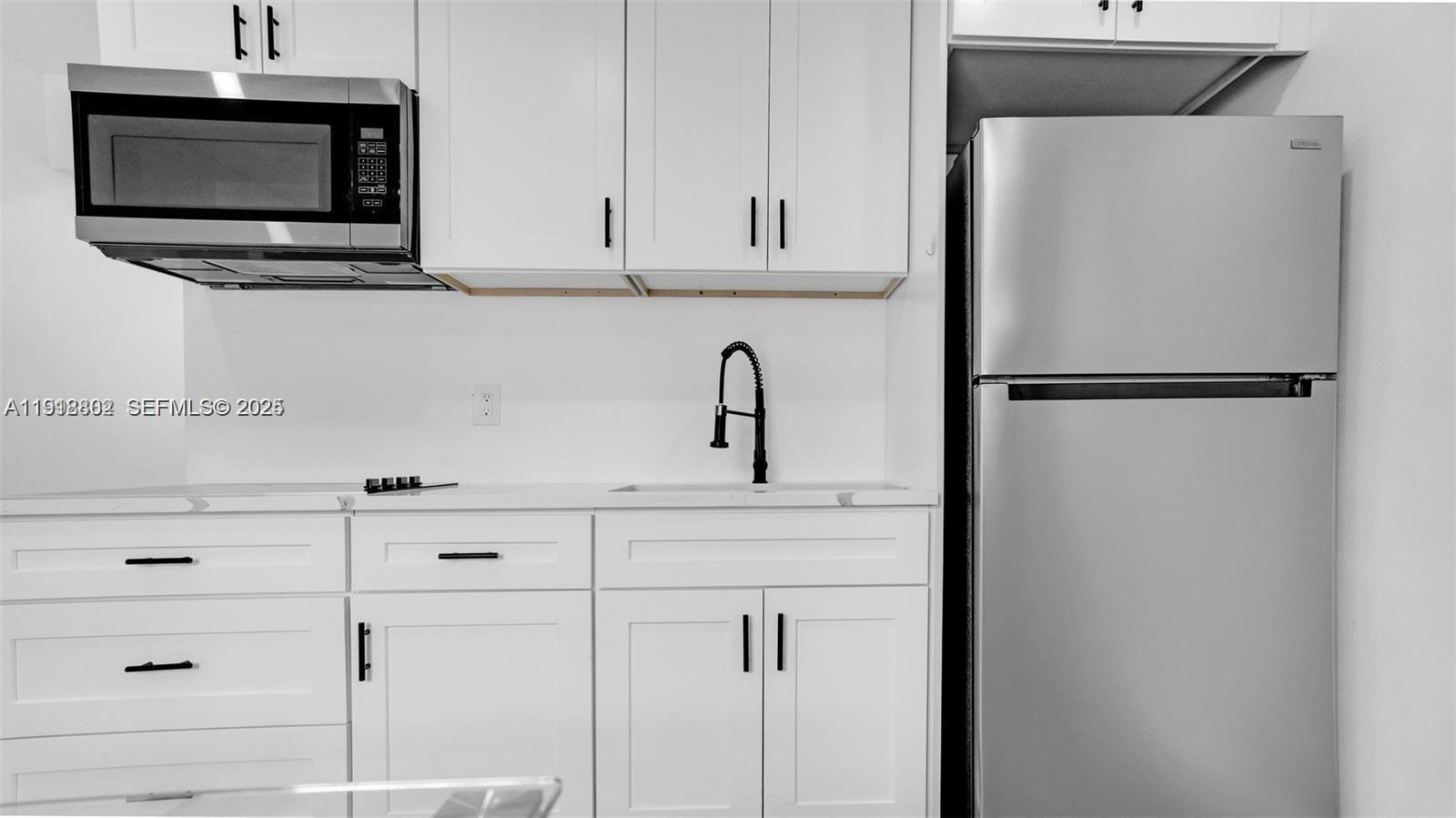 32 Southwest 9th Street, Unit 3 Hallandale Beach, FL 33009 - Photo 3 of 13 a white kitchen with microwave and cabinets