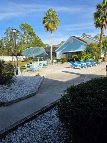 a backyard of a house with table and chairs under an umbrella