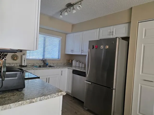 a kitchen with granite countertop stainless steel appliances a refrigerator a sink a stove a counter space and cabinets
