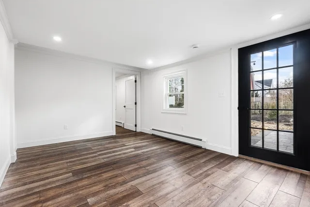 a view of an empty room with a window and wooden floor