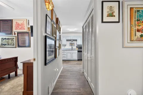 a view of a hallway with wooden floor and living room