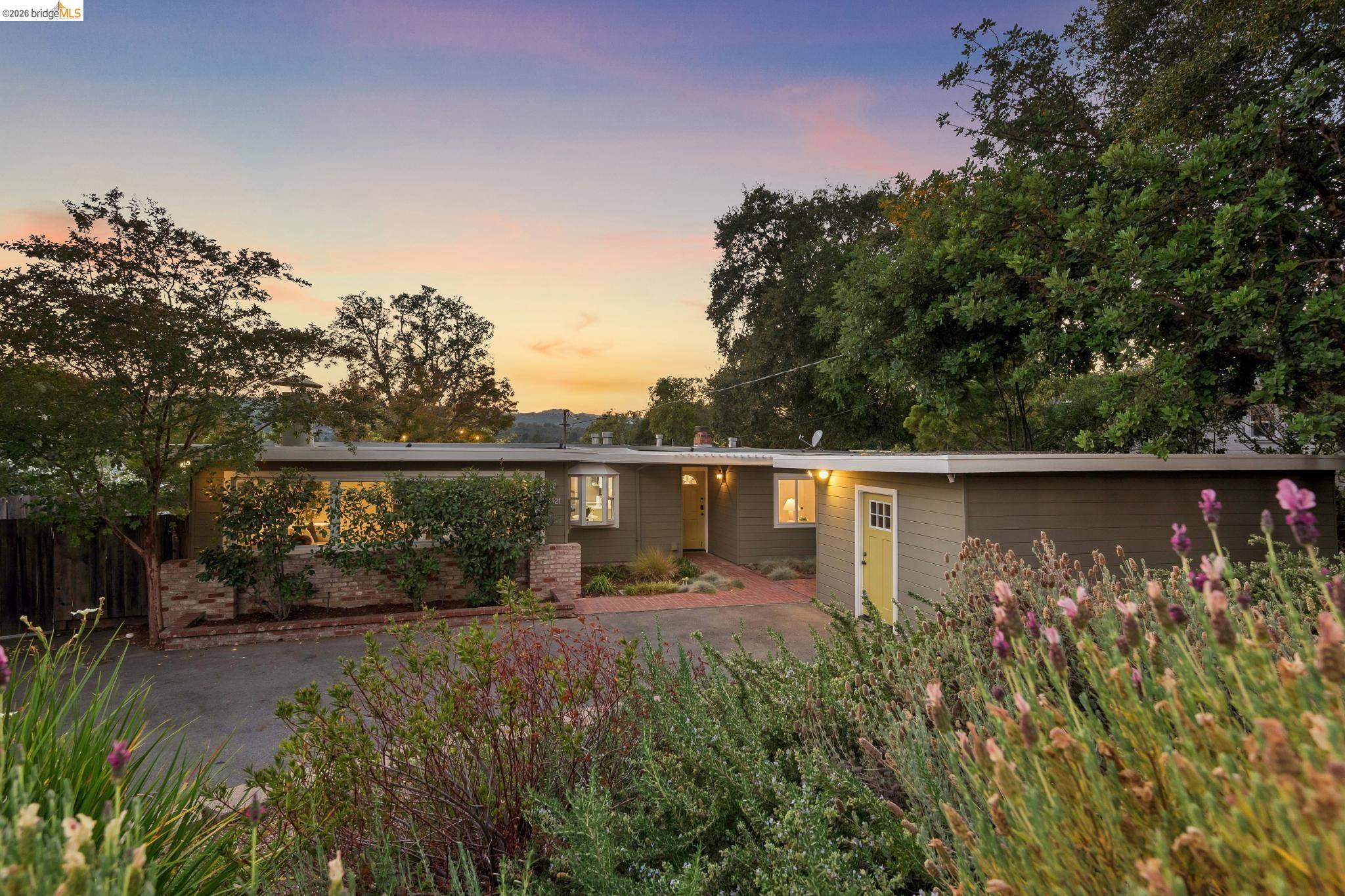 1321 Sunset Loop Lafayette, CA 94549 - Photo 1 of 49 Single-story residence featuring horizontal siding, a brick planter, a bay window, and a prominent yellow front door, set amidst mature landscaping