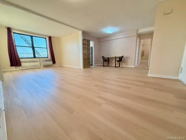 a view of an empty room with wooden floor and a window