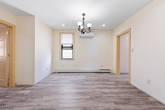 a view of an empty room with wooden floor and windows