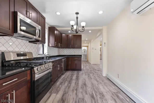 a large kitchen with stainless steel appliances granite countertop a stove and a wooden floors