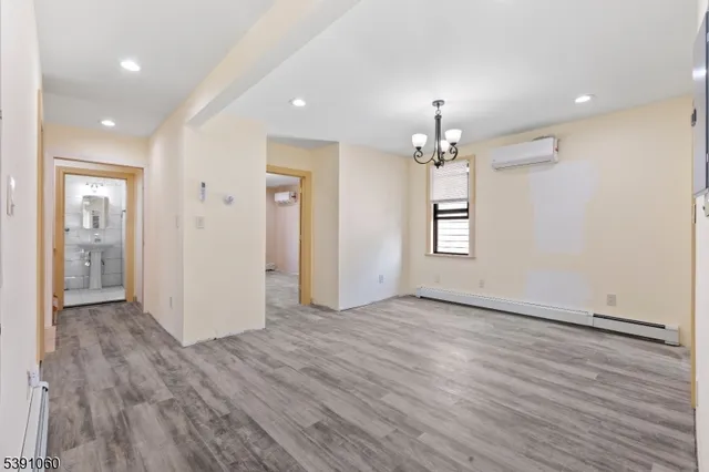 an empty room with wooden floor chandelier and windows