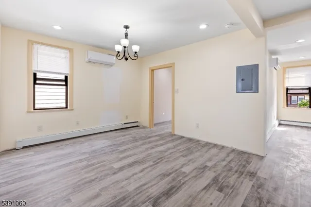 an empty room with wooden floor chandelier and windows