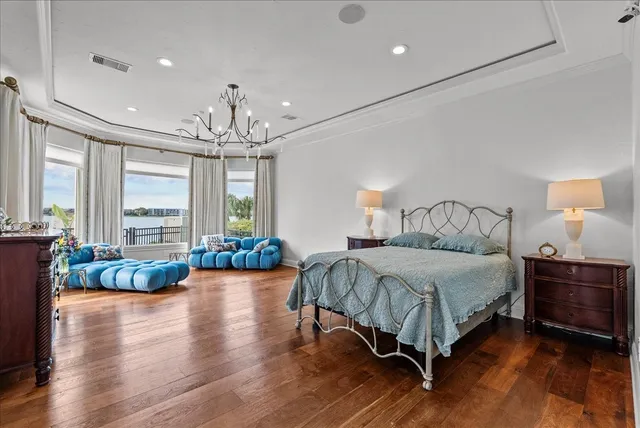 a spacious bedroom with a bed a chandelier and a large window