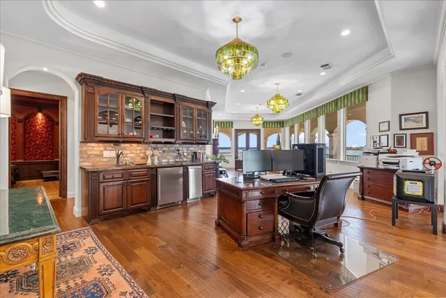 a kitchen with stainless steel appliances granite countertop a stove top oven a refrigerator a dining table and chairs with wooden floor