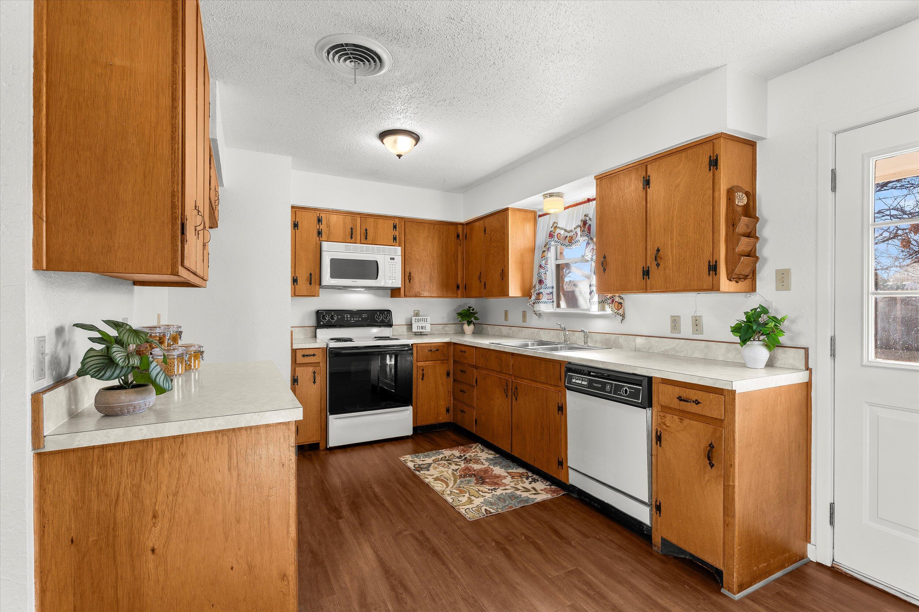 5519 17th Street Lubbock, TX 79416 - Photo 7 of 23 a kitchen with stainless steel appliances granite countertop a stove a sink dishwasher and a refrigerator with wooden floor