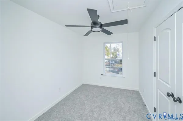 an empty room with windows and fan