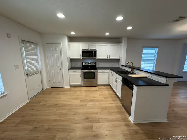 a kitchen with granite countertop a stove top oven a sink dishwasher a refrigerator and a microwave