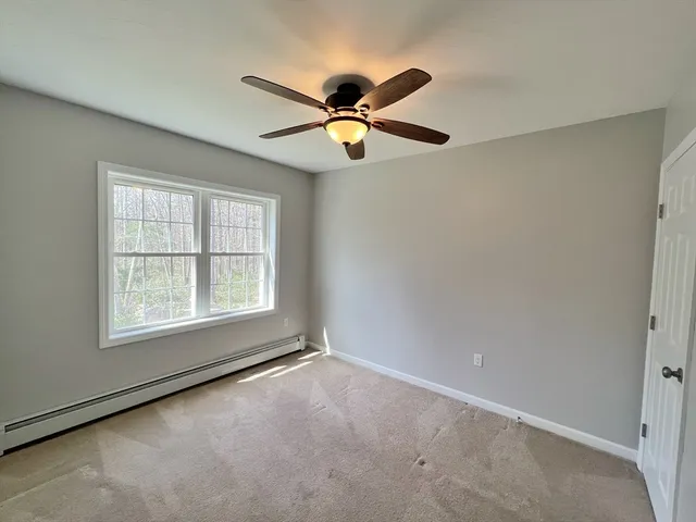 a view of an empty room with window and chandelier fan