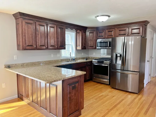a kitchen with stainless steel appliances granite countertop a refrigerator a sink and a stove