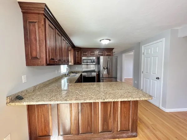 a view of kitchen island wooden cabinets granite counter tops and wooden floors