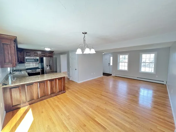 a view of a living room with kitchen area and a wooden floor