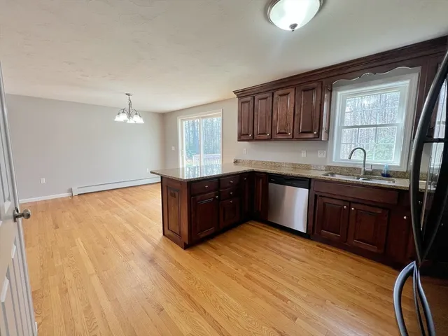 a kitchen with stainless steel appliances granite countertop a sink cabinets and wooden floor