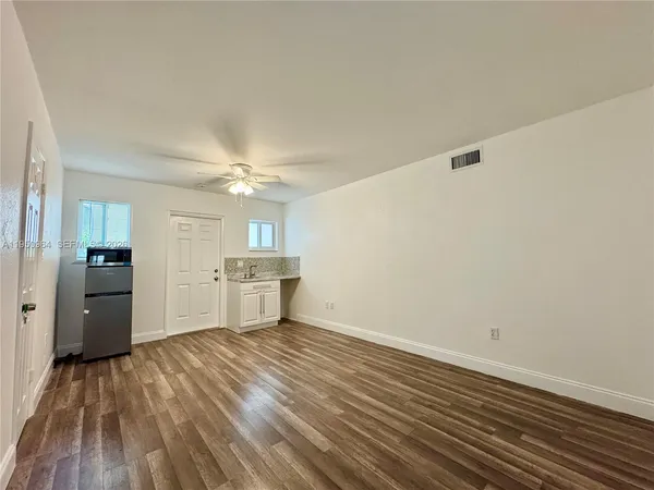a view of a room with wooden floor a ceiling fan and staircase
