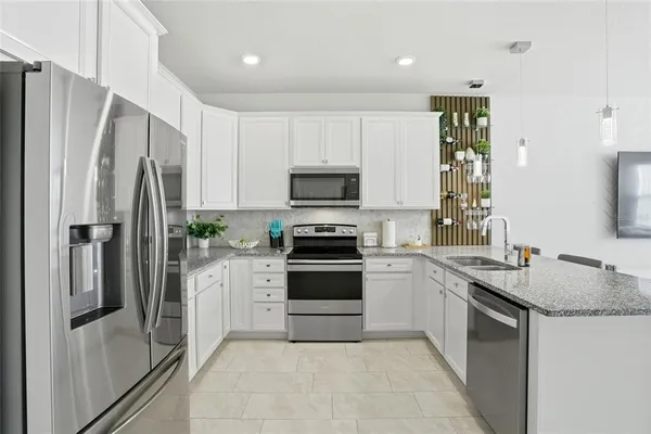 a kitchen with stainless steel appliances granite countertop a sink refrigerator and microwave