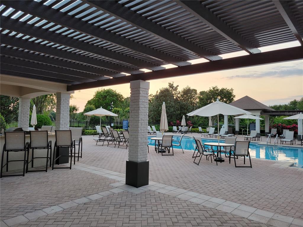 14239 Avenue Of The Groves Winter Garden, FL 34787 - Photo 47 of 54 a view of a patio with a table and chairs under an umbrella with a barbeque