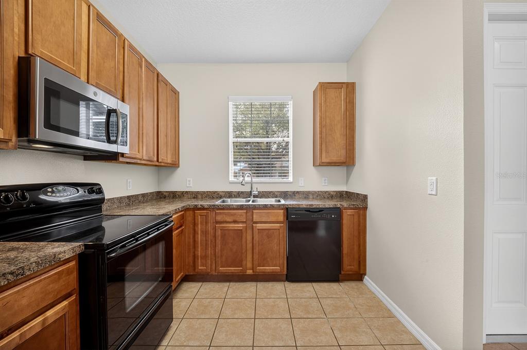 14239 Avenue Of The Groves Winter Garden, FL 34787 - Photo 7 of 54 a kitchen with stainless steel appliances granite countertop a stove a sink and a microwave