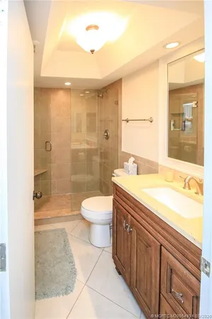 a spacious bathroom with a granite countertop sink a toilet a mirror and shower
