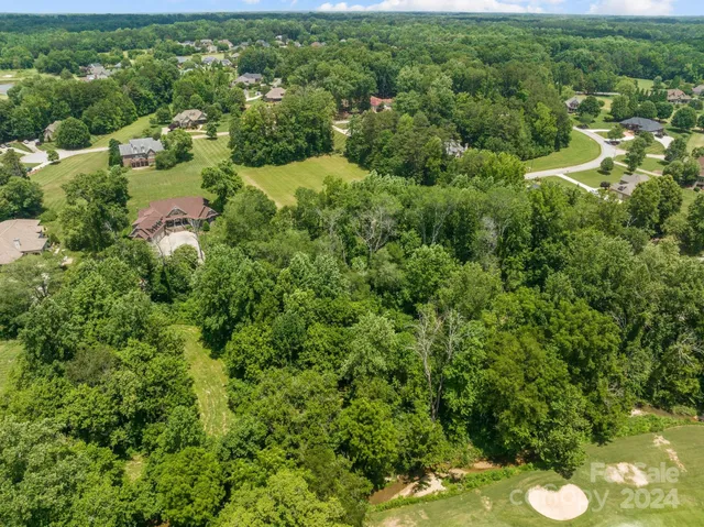 an aerial view of residential house with outdoor space and trees all around