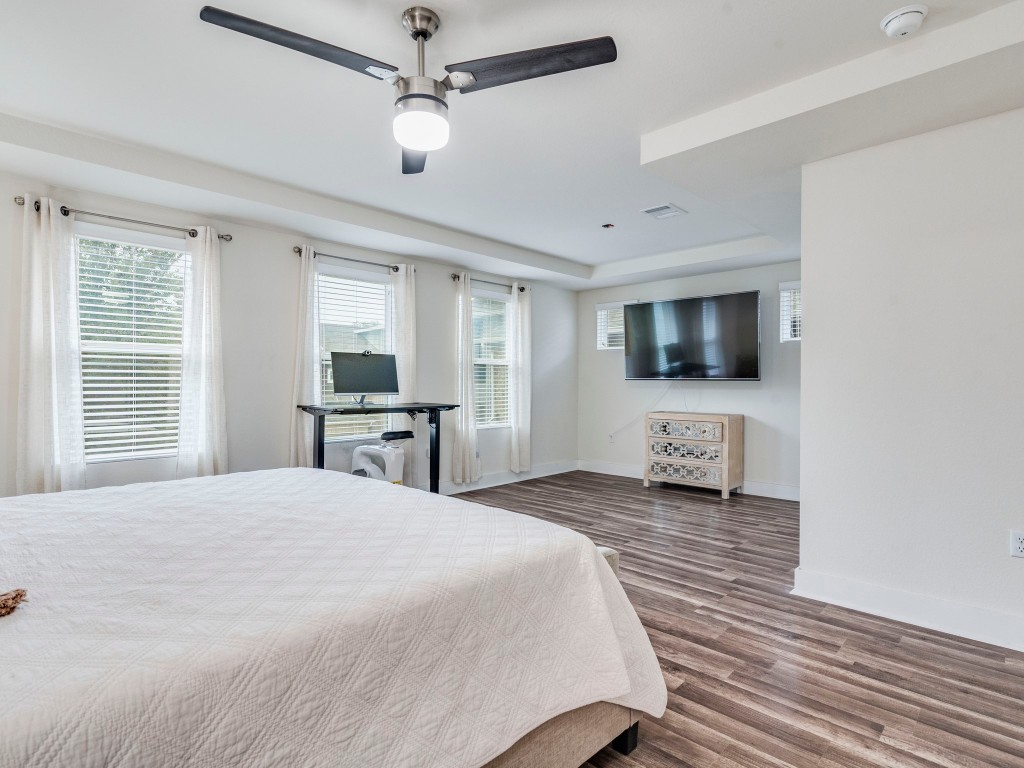 7408 Merrick Lane, Unit 42 Austin, TX 78745 - Photo 13 of 28 Bedroom featuring evp flooring, tv room and ceiling fan