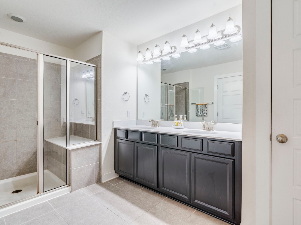 7408 Merrick Lane, Unit 42 Austin, TX 78745 - Photo 15 of 28 Full bathroom with double vanity, a shower stall wiht bench and plenty of great lighting