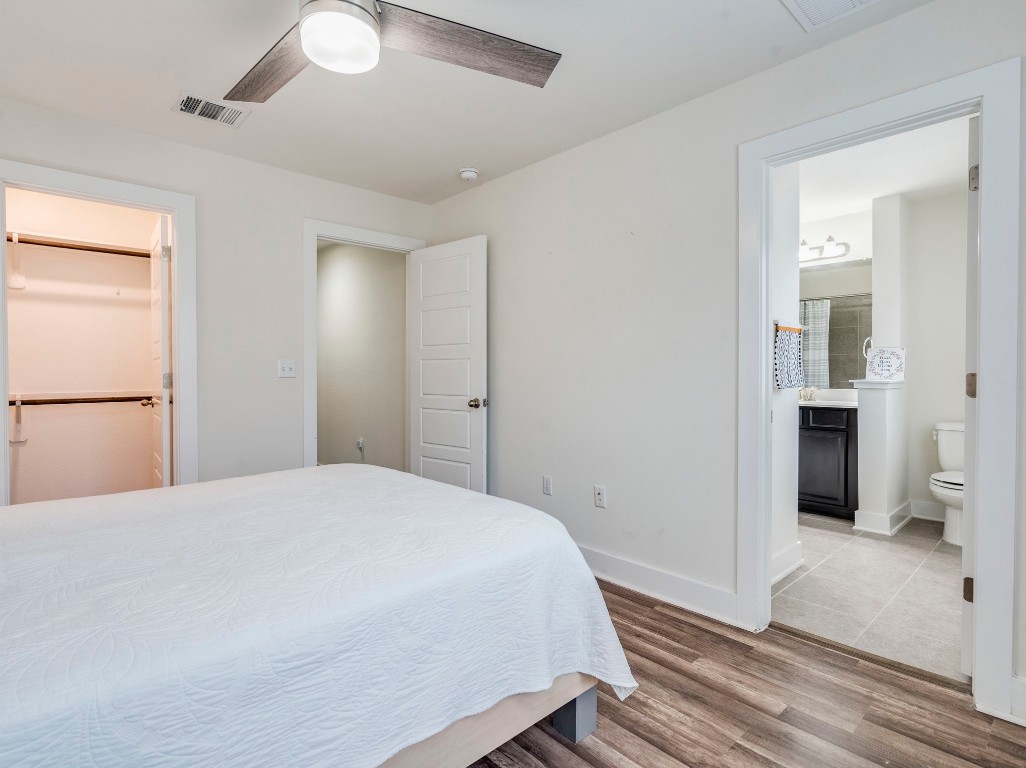 7408 Merrick Lane, Unit 42 Austin, TX 78745 - Photo 22 of 28 Bedroom featuring wood finished floors, a ceiling fan, connected bathroom, and a walk in closet