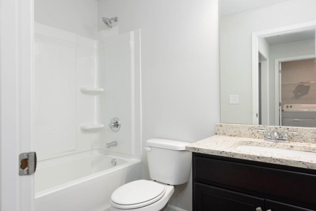 2773 Apperson Way Suwanee, GA 30024 - Photo 11 of 24 a bathroom with a granite countertop sink toilet a large mirror a bathtub and shower