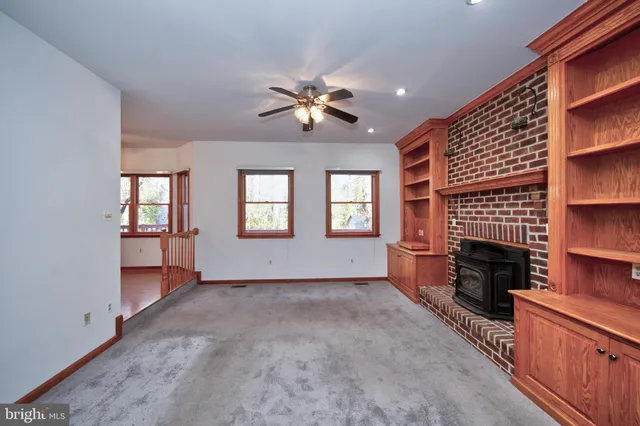 wooden floor in an empty room with a window and a kitchen