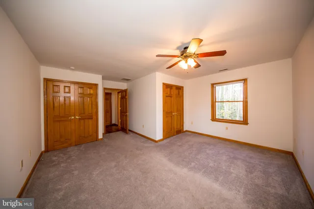an empty room with closet and a ceiling fan