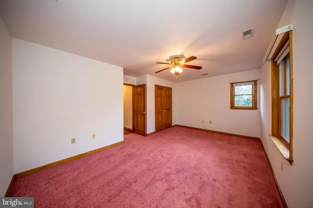 an empty room with chandelier fan and windows